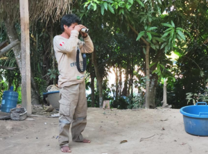 An Amazonian community member observes the forest with binoculars, participating in environmental monitoring and surveillance activities in his territory. Photo: Jofre Torres